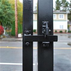 a close up of a black metal gate with a red fire hydrant in the background