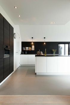 a large kitchen with white cabinets and black counter tops, along with wooden flooring