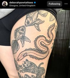 a woman's thigh with fish and snake tattoos on it