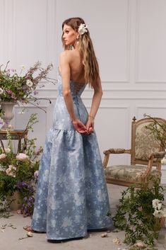 a woman in a blue dress standing next to a chair with flowers on the floor