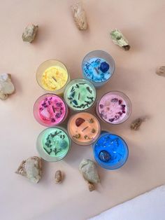 six small bowls filled with different colored ice creams on top of a white surface