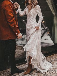 a man and woman standing next to each other in front of a mirror wearing wedding gowns