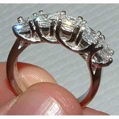 a hand holding a three stone ring in it's left hand