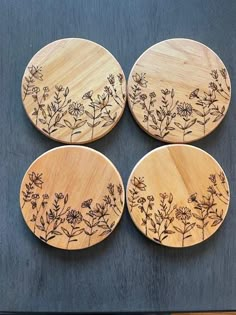 four wooden coasters with flowers on them sitting on top of a black countertop