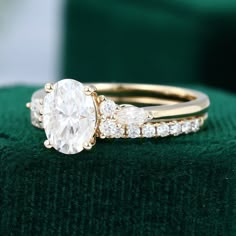 an engagement ring with three pear shaped diamonds on it, sitting on top of a green velvet cushion