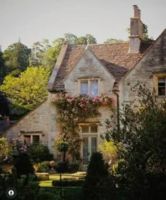 an old stone house with pink flowers on the windows