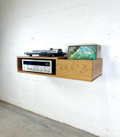 an old radio sitting on top of a wooden shelf next to a white brick wall