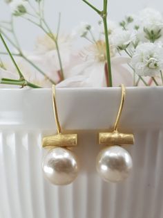 We combine contemporary designs with beautiful gemstones and metals to create desirable jewellery . Classic Round Pearl Gold Vermeil Earrings . Elegant white iridescent pearls with a brushed gold vermeil bar setting and a hook fitting  Pearl is the birthstone for June  Composition and size :   .18K gold plating on sterling silver , suitable for sensitive skin . .White Pearl     .Total earring length  2.5 cm .Pearl 1 cm in diameter  All our Jewellery is hand made , please allow natural slight var Modern Earrings With Elegant Design For Gift, Modern Elegant Earrings For Gift, Modern Round Earrings With Elegant Design, Formal Brass Pearl Drop Earrings, Modern Pearl Earrings With Ear Wire As Gift, Modern Gold Pearl Earrings In Sterling Silver, Modern Pearl Drop Earrings For Anniversary, Modern Gold Pearl Earrings For Wedding, Elegant Brass Pearl Earrings With Ear Wire