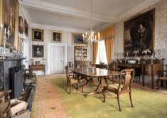 an old fashioned dining room with antique furniture and paintings on the walls, along with a fireplace