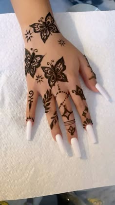 a woman's hand with hennap and butterfly tattoos on her left arm