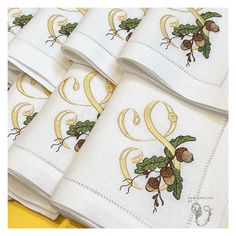 four white napkins with gold designs on them and the letter e in golden lettering