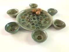 an assortment of small bowls and cups on a white surface with one bowl in the middle