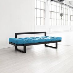 a red bench sitting on top of a hard wood floor next to large open windows