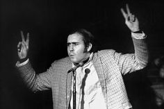 a black and white photo of a man giving a speech with his hands in the air