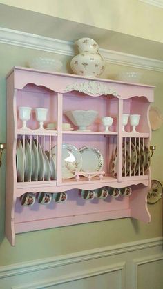 a pink china cabinet filled with dishes and plates