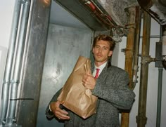 a man in a suit holding a brown paper bag