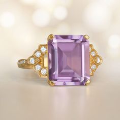 An Stunning 18k Yellow Gold Ring Centering An Emerald Cut Amethyst Elegant Yellow Gold Amethyst Ring With Accent Stones, Luxury Emerald-cut Amethyst Ring For Formal Events, Luxury Emerald Cut Amethyst Ring For Formal Occasions, Luxury Purple Amethyst Ring, Rectangular Shape, Elegant Yellow Gold Amethyst Ring With Gemstone Accents, Luxury Purple Amethyst Rectangular Ring, Luxury Purple Rectangular Amethyst Ring, Elegant Rectangular Amethyst Ring For Formal Occasions, Luxury Rectangular Amethyst Ring