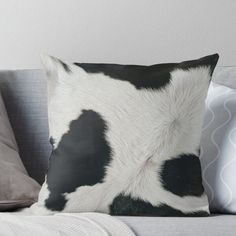 a black and white cow print pillow sitting on top of a couch