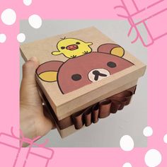 a hand holding a box with a bear and chick on it