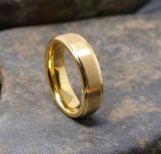 a gold wedding ring sitting on top of a rock