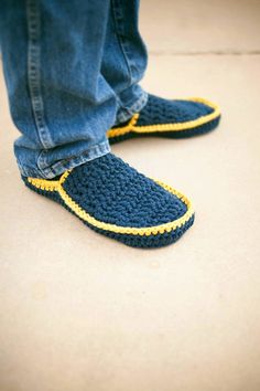 a pair of feet wearing blue slippers with yellow stitching on the soles