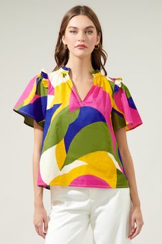 Introducing the whimsical wonder of the Rio Abstract Split Neck Poplin Top– where comfort meets color in a playful dance of poplin cotton perfection! Adorned with small ruffle ends on the shoulders and around the neckline plus a smooth outlined deep v-cut frame. So, go ahead, seize the day, and let your vibrant spirit shine through!- Ruffle detail- Split neckline- Short sleeves- Relaxed fit- Color: Khaki MultiSize + Fit - Model is 5'8" and wearing size XS- Measurements taken from size S - Chest: Printed Cotton Top With Flutter Sleeves, Multicolor Cotton Ruffle Sleeve Tops, Multicolor Cotton Top With Ruffle Sleeves, Multicolor Cotton Tops With Ruffle Sleeves, Summer Poplin Short Sleeve Tops, Summer Poplin Blouse, Playful Multicolor Ruffled Tops, Poplin Blouse For Summer, Multicolor Cotton Flutter Sleeve Top