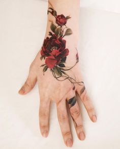 a woman's hand with red flowers on it and leaves all over the wrist