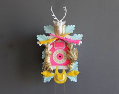 a colorful clock hanging from the side of a wall with antlers on it's face