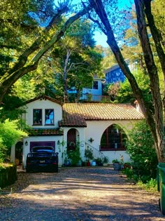 a car parked in front of a white house surrounded by trees and bushes on a sunny day