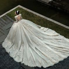 a woman in a wedding dress is standing on the steps looking down at her gown