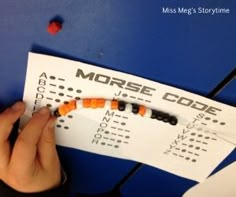 a person is making a morse code on a piece of paper with orange and black beads