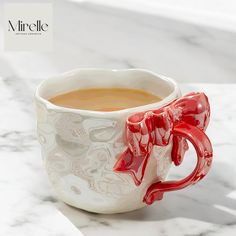 a red and white ceramic cup on a marble counter top with the word airclele written below it