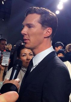 a man in a suit and tie talking to someone on the phone at an event