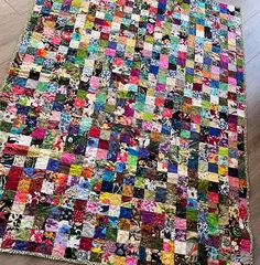 a multicolored patchwork quilt is laying on the floor