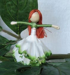 a doll is sitting on top of a plant with green leaves in the foreground