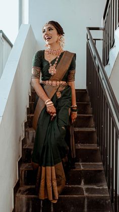 a woman in a green and brown sari is standing on some stairs with her hand on her hip