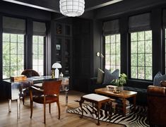 a living room filled with lots of furniture next to two windows and a zebra rug on the floor