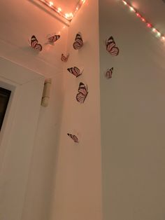 several butterflies are hanging on the wall next to a door with lights around them and one is upside down