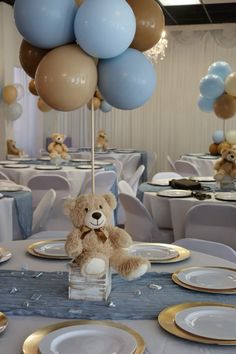 a teddy bear sitting on top of a table with plates and silverware in front of it