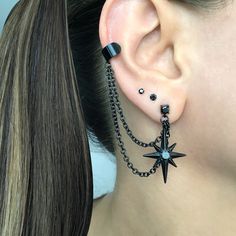 a close up of a person wearing ear piercings with chains and stars on them