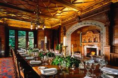 a long table with place settings and candles on it in a large room filled with windows