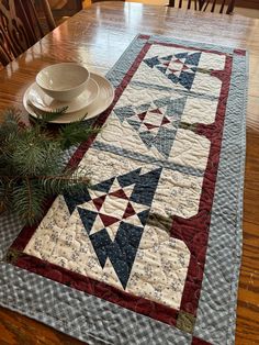 a quilted table runner on top of a wooden dining room table with plates and placemats