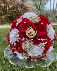 red and white bridal bouquet with crystal brooches on it in the grass