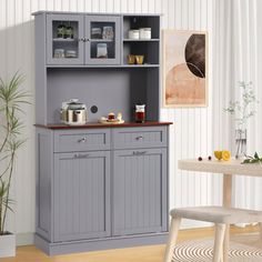 a gray cabinet with two doors and shelves in the middle of a room next to a table