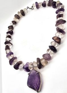 Amethyst and clear rock crystal beaded handcrafted artisan necklace. Stunning large natural tumbled crystals are strung on a thick memory wire. Large amethyst pendant is in the center of the necklace. Gemstones tested with Presidium II gemstone tester. Necklace measures a wearable 19.5 inches long. Pendant measures approx 1 and 1/2 of an inch tall and 1 and 1/8th of an inch wide. Clear Gemstone Beads Jewelry For Healing, Healing Clear Gemstone Beads Jewelry, Handmade Healing Crystals, Clear Gemstone Necklaces For Healing, Unique Amethyst Beaded Necklaces, Unique Beaded Amethyst Necklace, Unique Amethyst Beaded Necklace, Spiritual Clear Gemstone Necklace, Adjustable Amethyst Jewelry With Large Stone