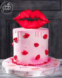 a pink cake with red lipstick on it and the top layer is covered in icing