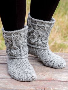 the legs and feet of a woman wearing gray crocheted slippers