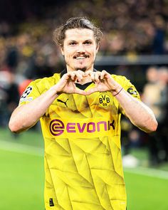 a man in a yellow soccer uniform standing on a field with his hands folded over his chest