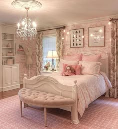 a bedroom decorated in pink and white with a chandelier hanging from the ceiling