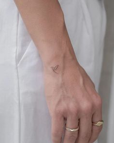 a woman's hand with a tiny bird tattoo on her left wrist and the other arm